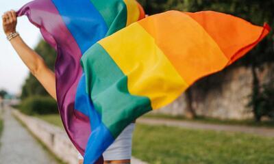 Vrouw die zwaait met regenboogvlag holebigemeenschap